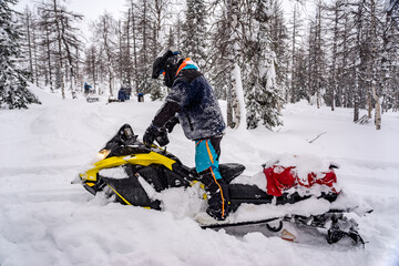 Mountain snowmobile riders ride on the slopes