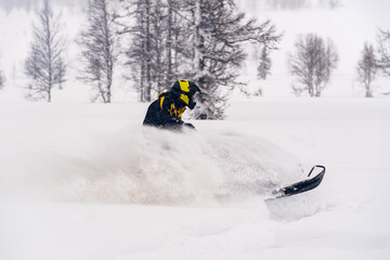 Mountain snowmobile riders ride on the slopes