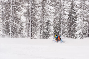 Mountain snowmobile riders ride on the slopes