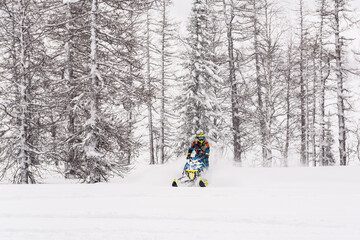 Mountain snowmobile riders ride on the slopes
