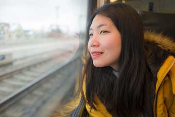 young beautiful and happy Asian Japanese woman sitting on train looking out to window enjoying holidays travel in Europe smiling thoughtful and sweet