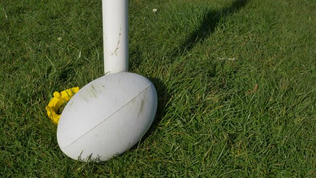 Close Up Shot of Rugby Ball Rolling into Frame Next to Tee and Post