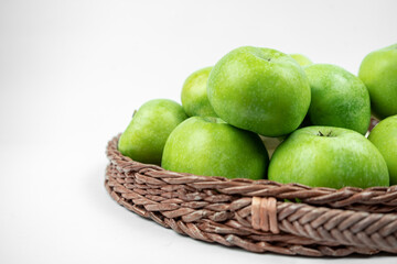 Group of ripe green apples in a basket on white background