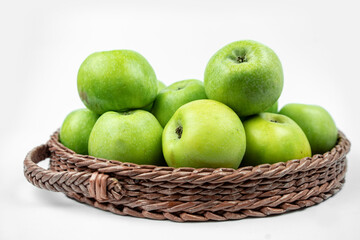 Group of ripe green apples in a basket on white background