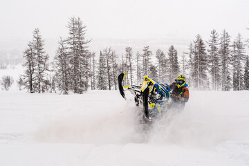Mountain snowmobile riders ride on the slopes