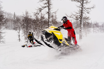 Mountain snowmobile riders ride on the slopes