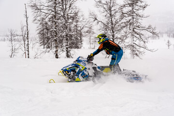 Mountain snowmobile riders ride on the slopes