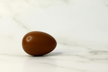 Chocolate egg on a white background with a round glare from the light