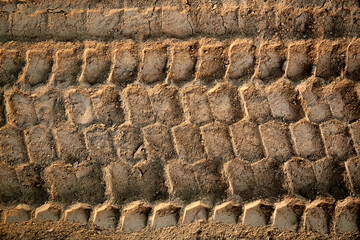 Tire tread footprints of a dump truck on the sand. Construction site. Pattern. Brown abstract background. Car wheelprint. Textured ground. Tyre drawing