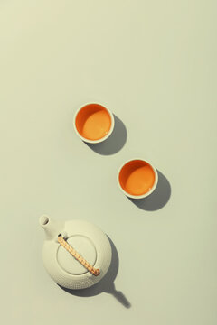 Tea concept, two white cups of tea and teapot on concrete background