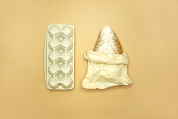 The concept of shopping without waste - bread in paper packaging and eggs in carton packages, top view. beige background