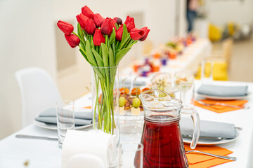 vase with a bouquet of red tulips on the festive table. serving the table with appetizers, canapes, salads in jars. Catering. restaurant business.