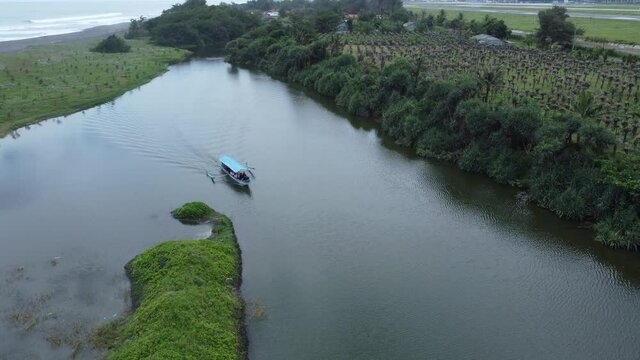 Small lonely motor boat travelling down a narrow lake near a sea. Aerial footage.