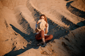 Dunes and lines, scenic landscape. Background of sandy hilly desert. Young woman sitting and gazing...
