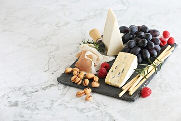 Appetizers platter with various of cheese, prosciutto, fruits and nuts. Cheese board. Selective focus