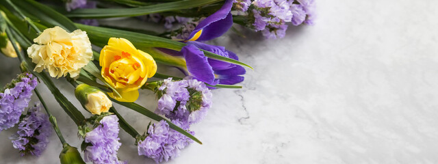 Yellow narcissus flowers and purple irises in a line floral arrangement isolated on marble background. Flowers composition.woman day, mothers day, easter concept. copy space.web banner