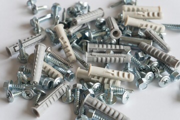 Screws and wall plugs piled up on a white background. Work concept