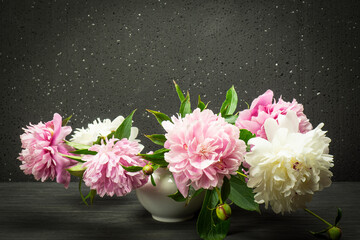 Still life with white and pink peony flowers in a vase, on a dark gray background