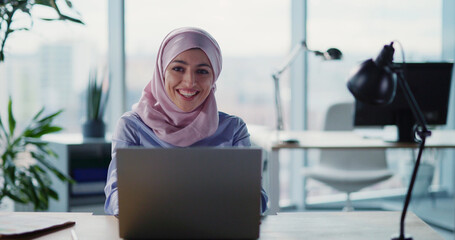 Islamic young excited woman wearing hijab winning money online receiving good news on corporate...