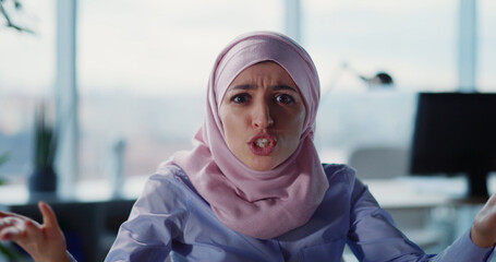 Portrait of angry arabic businesswoman in hijab sitting at office shouting and kicking out employee. Emotional female boss. Expressions.