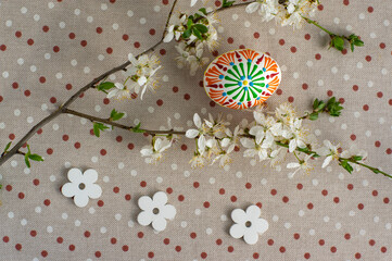 Homemade handmade painted Easter eggs on spotted tablecloth decorated with blackthorn sloe branch and wooden flowers
