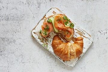 Croissant sandwich with smoked salmon,  cheese, egg, cucumber and micro greens. Flat layot, copy...
