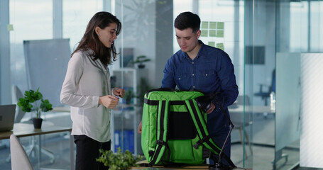 Obraz premium Caucasian woman delivering food package from corier in corporate office business center. Quick fast food. Convenient services.