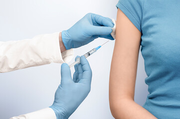 doctor makes an injection into the patient's hand on a gray background. vaccination of diseases