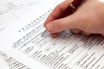 Obraz premium A man holding a ballpoint pen to fill a visa application form to China.