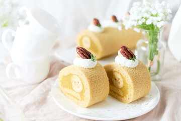 Fototapeta na wymiar Banana Swiss Roll Cake with banana cream filling set on white cafe table.