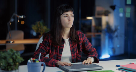 Fototapeta premium Young exhausted caucasian woman working long hours in office. Angry female employee closing laptop finishing work and frustrating.