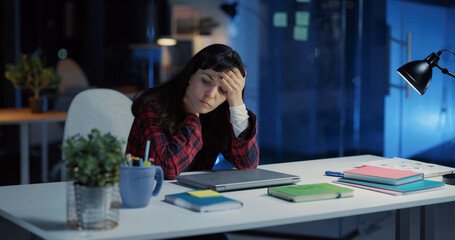 Young exhausted caucasian woman working long hours in office. Angry female employee closing laptop finishing work and frustrating.