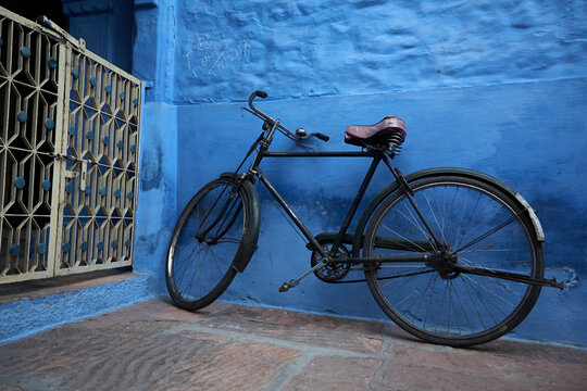 Old bicycle leaning against blue house wall in India. What a blue, as deep as the ocean. Normal perspective. Outside. 