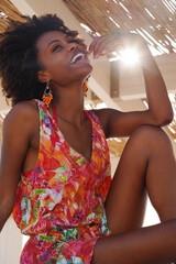 Portrait of a young black woman by the beach wearing colorful clothing