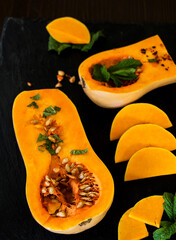 aufgeschnittener butternuss kübis mit minze vor schwarzen hintergrund