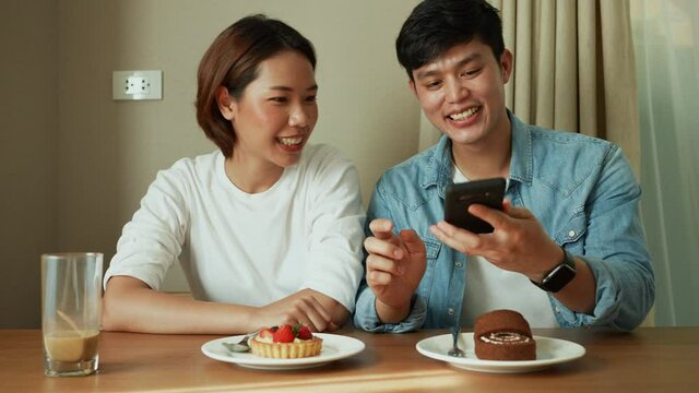 slow motion scene on group of asian lover sitting in dining room to talking with happiness and use smartphone to take picture and upload on social media application for lifestyle in vacation concept