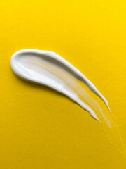 Swabs of creamy textures. Strokes of body lotion or hand cream. Smear of skincare cosmetics product. Cosmetology wellness and beauty concept. Isolated on yellow.