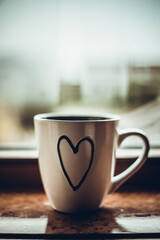 Steaming coffee cup on a rainy day window background