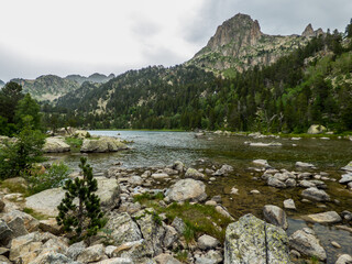 Un lago de montaña entre rocas graníticas rodeado de bosques de coníferas en el Parque Nacional de Aigües Tortes, en el Pirineo español