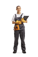 Full length portrait of a young repairwoman with a tool belt holding a clipboard