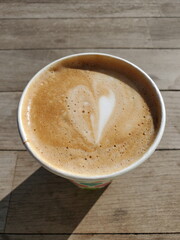 Double espresso with whipped milk foam. Coffee drink called Flat White. Coffee to go in takeaway cup. Selective focus to milk foam surface with bubbles and coffee aroma