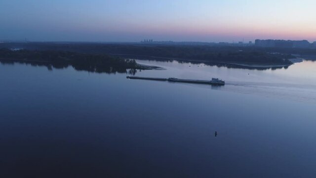 Aerial view. Tug pushing a barge on the river at sunrise.