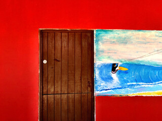 old wooden door in red parde and with blue sky and painted kite surf.