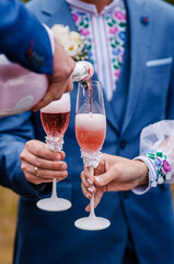 Glasses with red wine in the hands of the newlyweds and their friends