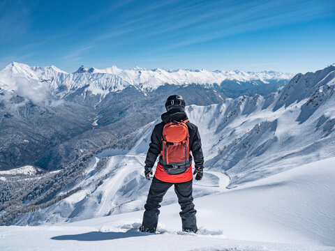 Back view of snowboarder at mountains background in ski resort of Krasnaya Polyana, Russia