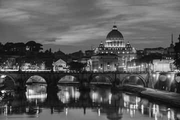 Fototapeta na wymiar A black and white evening view of St. Peter's Basilica, Vatican City, Holy See, from a bridge over the Tiber river, Rome, Italy 