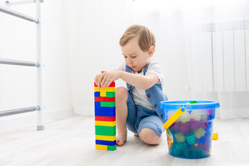 a child with a constructor at home, a cute boy plays or collects a colored constructor