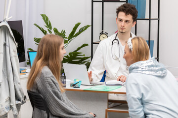 Fototapeta premium A mother and daughter are talking in a doctor's office about an illness the doctor has pointed out. The primary care physician