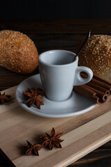 Coffee mug with anise, cinnamon and muffins on an old table. 