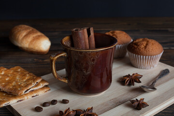 Brown glass for tea or cocktails with cinnamon sticks, croissant and anise stars. Wooden background. 